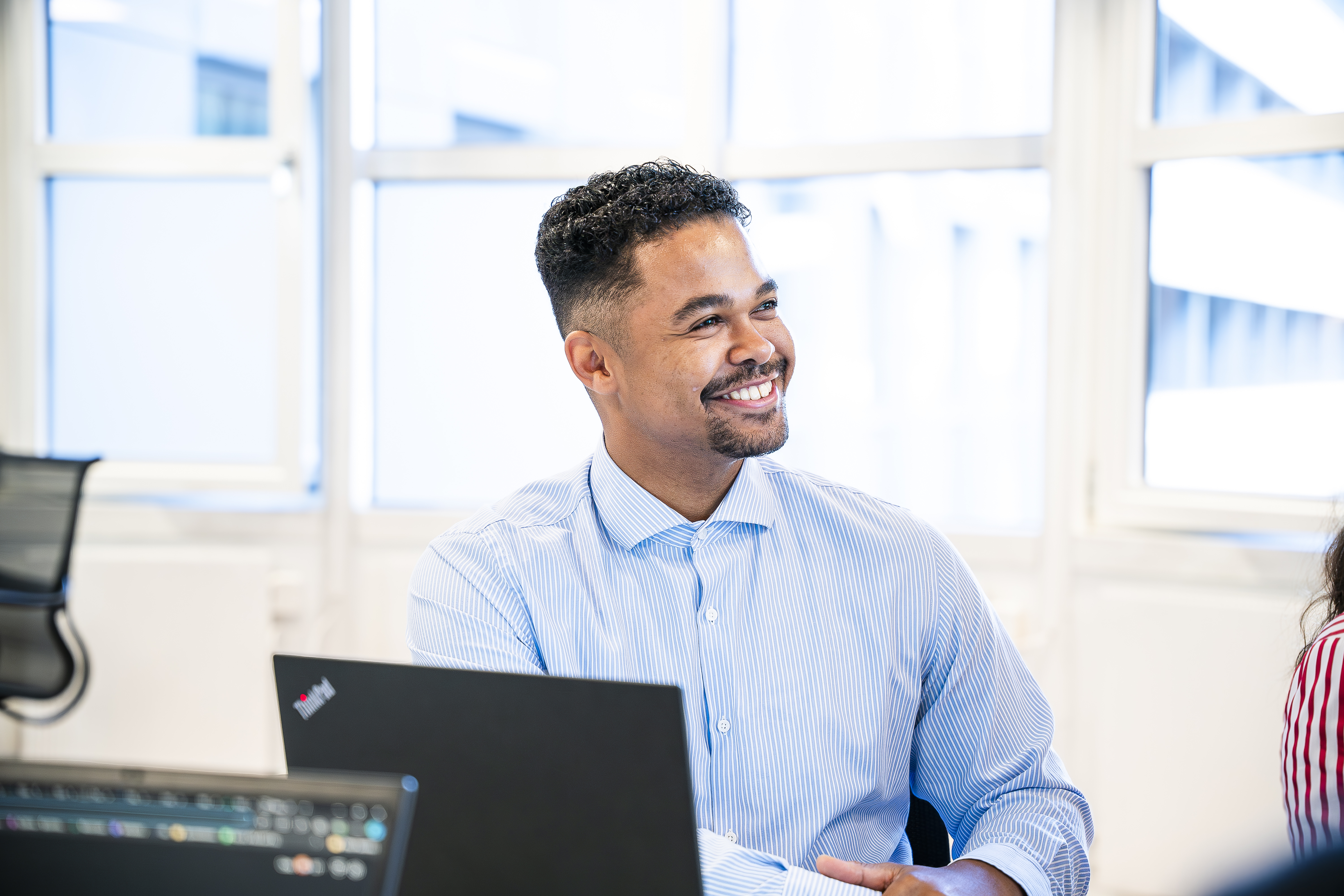 Mann sitter ved en pc og smiler